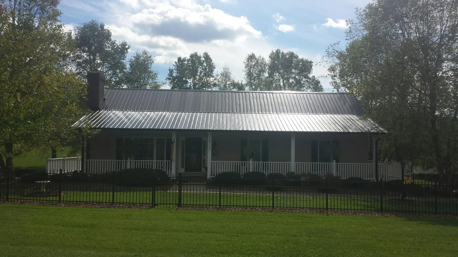 Gray metal roof on a brick ranch with a full width front porch — Gutter Guard Installation work by our crew in Pleasant Hill