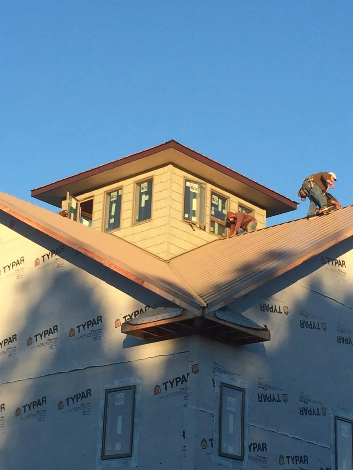 Roofers working around a rooftop cupola on a new metal roof at sunset — Roof Waterproofing in Pleasant Hill by Roofing Brothers